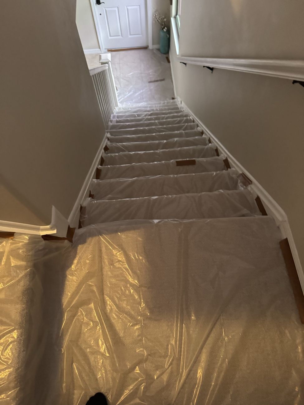 Plastic sheeting taped over the stairs and floors of an occupied home before insulation work begins