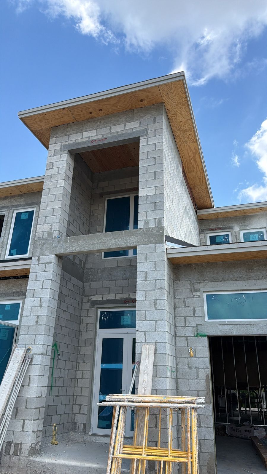 Two-story concrete block custom home under construction in Southwest Florida with impact windows installed and no insulation yet