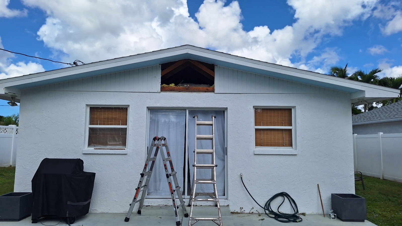 Southwest Florida house with the attic gable opened up for insulation work, ladders set against the wall