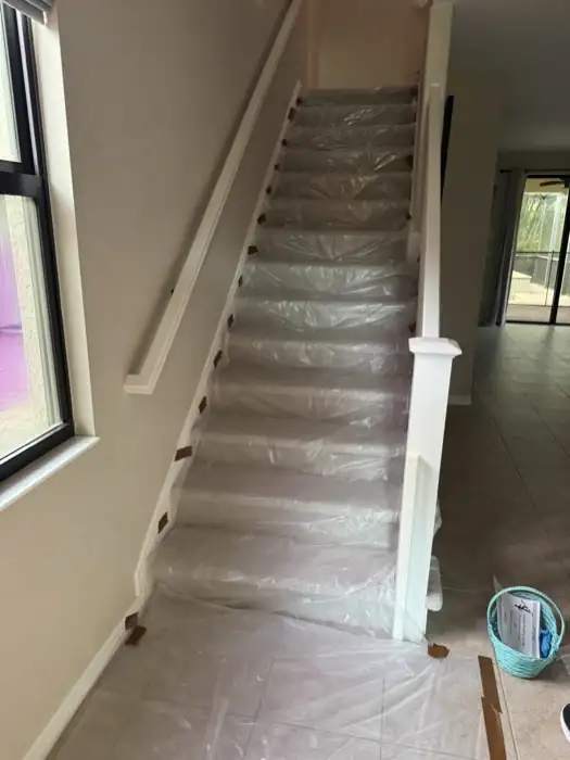 Residential staircase and tile floor covered with taped plastic sheeting before an attic job