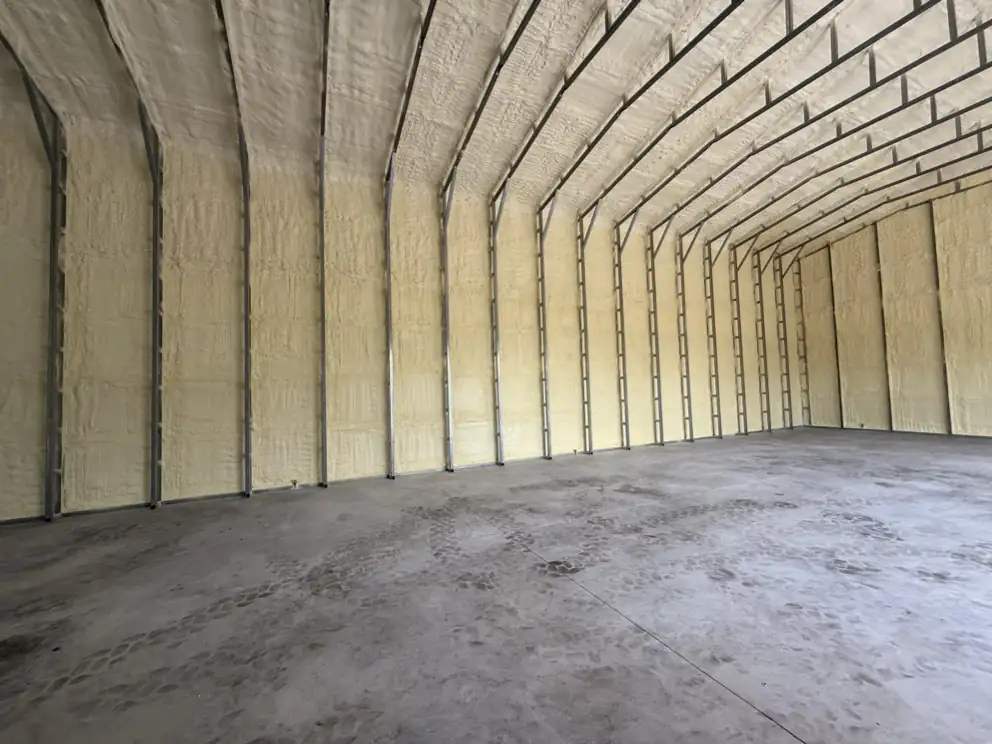 Closed-cell spray foam covering the walls and arched roof deck of a steel building in Southwest Florida, installed by Ideal Insulation